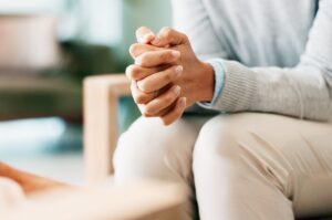 A woman sitting with her hands clasped. 