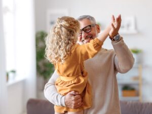 A grandfather playing with his granddaughter at home.